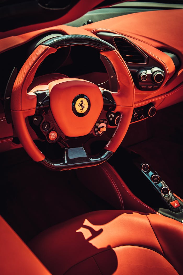 about-01 Close-up of a luxurious red interior of a sports car featuring a stylish steering wheel.